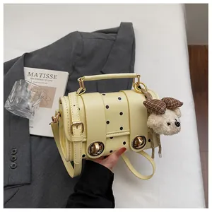 Close-up of retro yellow polka dot crossbody bag with cute teddy bear keychain charm