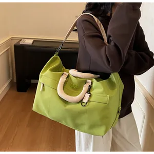 Grand sac de voyage vert citron porté à l'épaule par un mannequin en gros plan