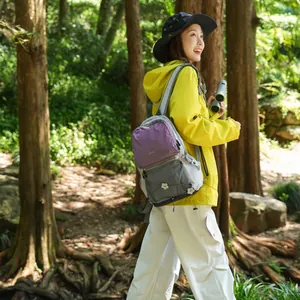 Detailansicht eines farbenfrohen Wanderrucksacks, den eine junge Frau im Wald trägt.