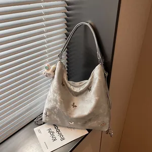 Detailed shot of a silver metallic hobo bag featuring 3D butterfly charms and soft texture