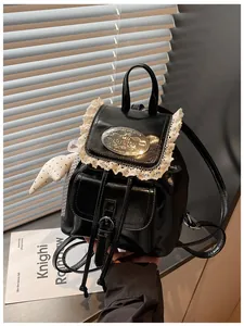 Close-up of black shiny PU leather backpack with lace trim and oval metal badge