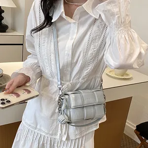 Elegant light blue woven leather crossbody bag worn by a model with a white vintage blouse