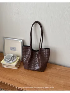 Elegant brown woven tote bag on a wooden desk with vintage books and coffee cup