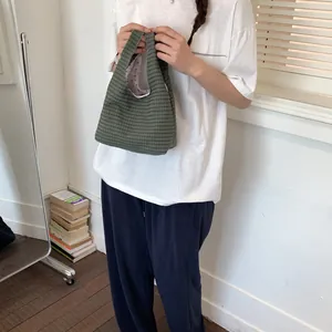 Detailansicht einer modischen grün karierten Canvas-Eimertasche für den täglichen Bedarf.