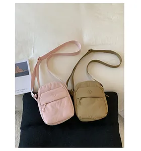A detailed view of two casual small crossbody square bags in pink and khaki colors