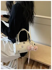 Detailed shot of white cylinder handbag featuring cute cat prints and pink bow charm