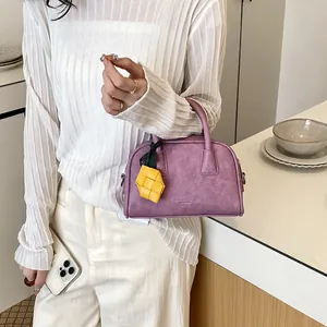 Detailed close-up view of a purple mini pillow bag with a yellow woven charm decoration