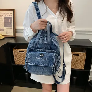 Model zeigt einen kleinen blauen Denim-Rucksack mit Waschung und mehreren Taschen