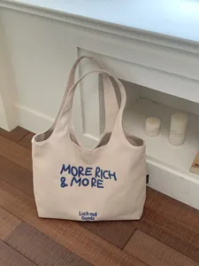Elegante bolso tote de lona beige con bordado azul 'More Rich & More' exclusivo