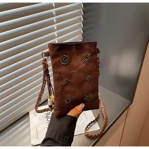 Hand-held view of a brown suede crossbody bag with delicate beaded star patterns