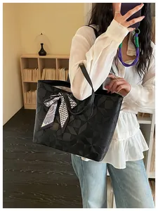 Fashionable black large-capacity tote bag with geometric embossed pattern and ribbon detail.