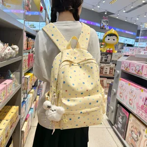 Back view of a yellow star pattern student backpack with a white fluffy charm