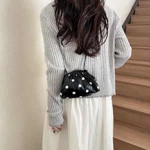 Black and white polka dot bucket bag shown on model in a casual indoor setting
