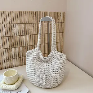 Detail view of cream white handcrafted knitted tote bag on a minimalist display