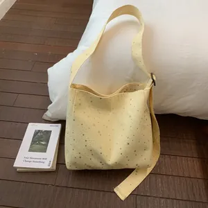 Close-up detail of a soft yellow canvas tote bag with sparkling silver sequin stars