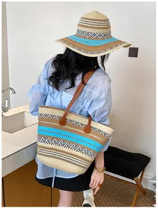 Modische gestreifte Strohtasche und passender Sonnenhut, getragen von einem Modell im Innenraum
