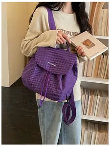 Detail of trendy purple checkered casual backpack worn by a model in library setting