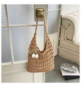 Primer plano de un gran bolso de hombro de punto calado beige con un colgante de tulipán