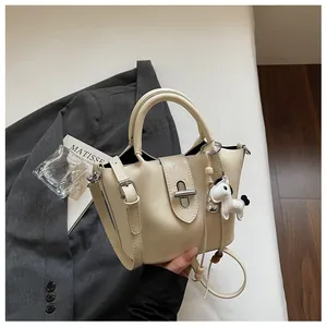 Vue détaillée d'un sac seau crème avec breloque cheval et détails argentés chic.