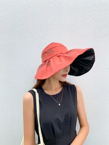 Fashionable woman wearing a coral pink large brim sun hat with black vinyl UV lining