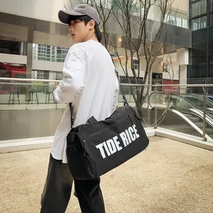 Grote zwarte reistas met TIDE RICE print gedragen door een man in stedelijk gebied.