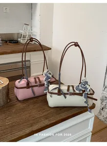 Detail view of pink and cream Boston handbags with checkered ribbons on a wooden table.
