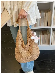 Dettaglio di una grande borsa tote in paglia intrecciata con portachiavi a coniglio.