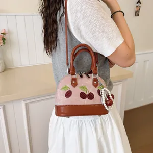 Elegante bolso de mano rosa con bordado de cerezas y colgante de perlas en modelo