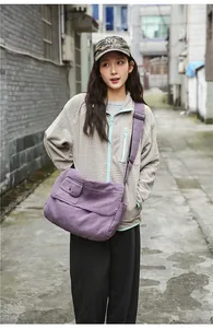 Large purple canvas messenger bag styled on a person in an urban outdoor street setting