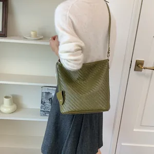 Detailweergave van een groene geweven emmertas in vintage stijl gedragen door een model