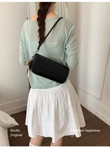 Trendy black rectangular small square bag worn as a crossbody bag by a female model