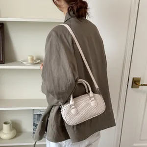 Lifestyle-Ansicht einer beigen geflochtenen Handtasche, gestylt von einem Model im modernen Interieur