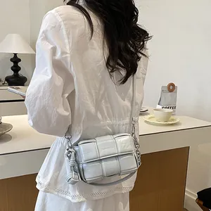 Detailed view of a light blue woven crossbody bag worn by a model in a cafe setting