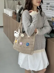 Detailansicht einer handgewebten Baumwolltasche mit Häkelblumen, getragen vom Model
