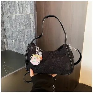 Detail view of a black jacquard hobo armpit bag with a traditional lucky charm