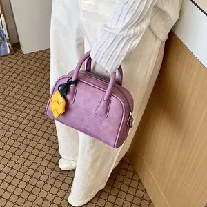Chic purple pillow handbag featuring a unique yellow woven decorative charm detail.