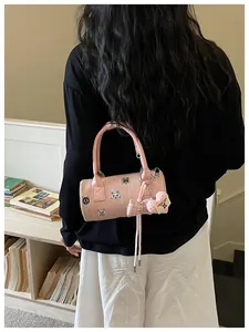 Detailed view of pink cylinder handbag with cat patches and plush heart charm