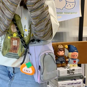 Detailansicht der lila Bucket-Umhängetasche mit orangefarbenem Katzen-Plüsch-Schlüsselanhänger