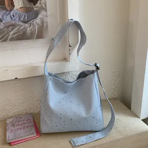 Detailed view of a light blue canvas tote bag with shiny silver star patterns