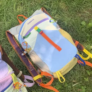 Close-up detail of a colorful dopamine style outdoor hiking backpack on green grass.