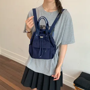 Mochila minimalista de nailon azul marino con cordón mostrada en un modelo para diario