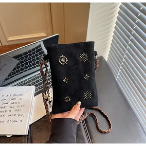 Close-up of black velvet crossbody phone bag with beaded sun patterns and braided strap