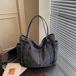 Grand sac cabas en denim noir délavé avec plusieurs poches pour un trajet stylé.