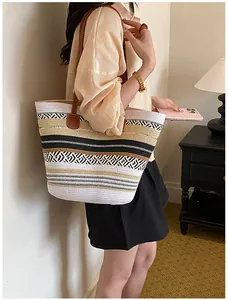 Detaillierte Seitenansicht einer großen gestreiften Strohtasche, getragen von einem Modell
