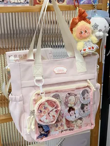Detail of a pink Ita bag tote featuring a transparent window with anime character badges.