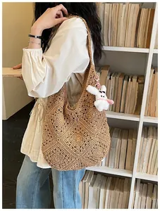 Grande borsa tote in paglia intrecciata marrone con motivi all'uncinetto e ciondolo a coniglio.