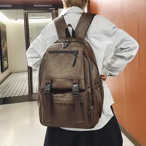Vue détaillée d'un grand sac à dos rétro en simili cuir marron porté par un modèle