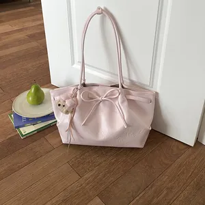 Detail van roze kunstlederen shopper met strikdetail en pluchen beer hanger