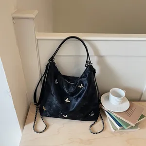 Detailed view of black multi-functional bag featuring elegant silver butterfly motifs