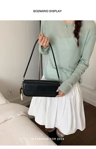 Detailed scenario display of a black underarm handbag held by a model in a white skirt